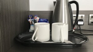 A coffee station with two white mugs, a stainless steel coffee pot, and a tray. - The Eaton Townhouse (London)