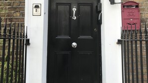 A black door with a white frame, a small mailbox, and a metal gate. - The Eaton Townhouse (London)