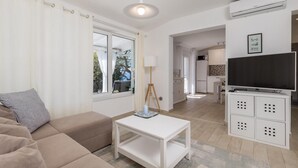 Un salon moderne avec un canapé, une table basse, une lampe et un téléviseur.