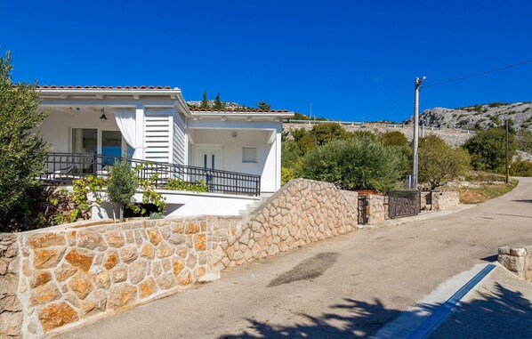 A white building with a stone wall, a balcony, and a clear blue sky. - Gorgeous home in Lukovo Sugarje (Lukovo Sugarje)