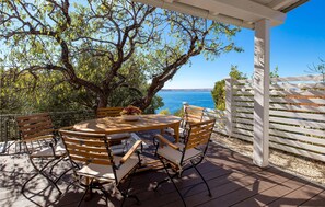 An outdoor patio with a round wooden table and chairs, a white pergola, and a view of the sea. - Gorgeous home in Lukovo Sugarje (Lukovo Sugarje)