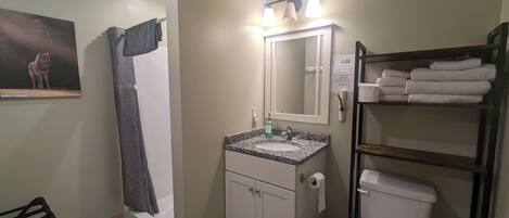 Une salle de bain équipée d’un lavabo, d’un miroir, de toilettes et d’un porte-serviettes.