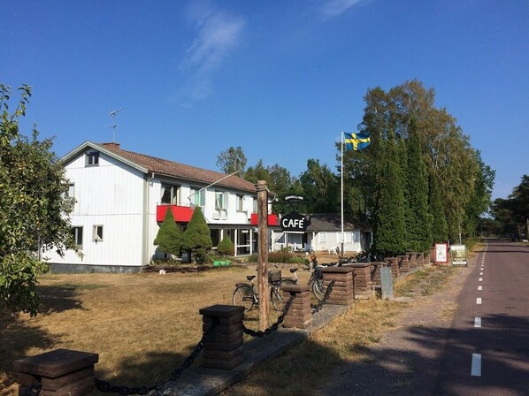 A white building with a red awning and a sign that reads "CAFE". - Pensionat Grankullavik (Byxelkrok)