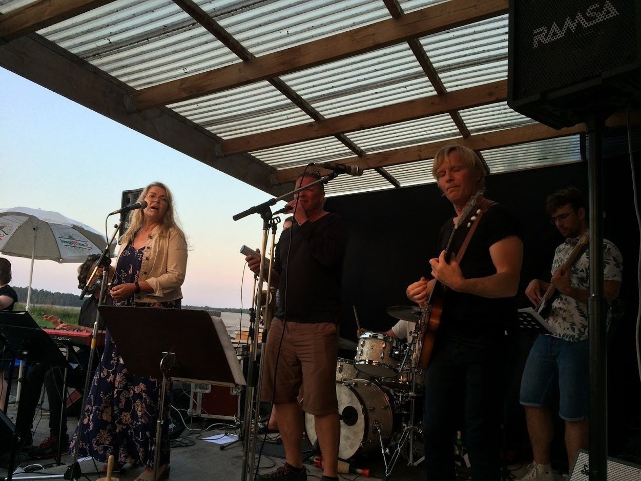 A band performing outdoors with a metal roof structure.