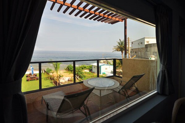 Un balcon avec une table et des chaises, offrant une vue sur la côte et un ciel dégagé.