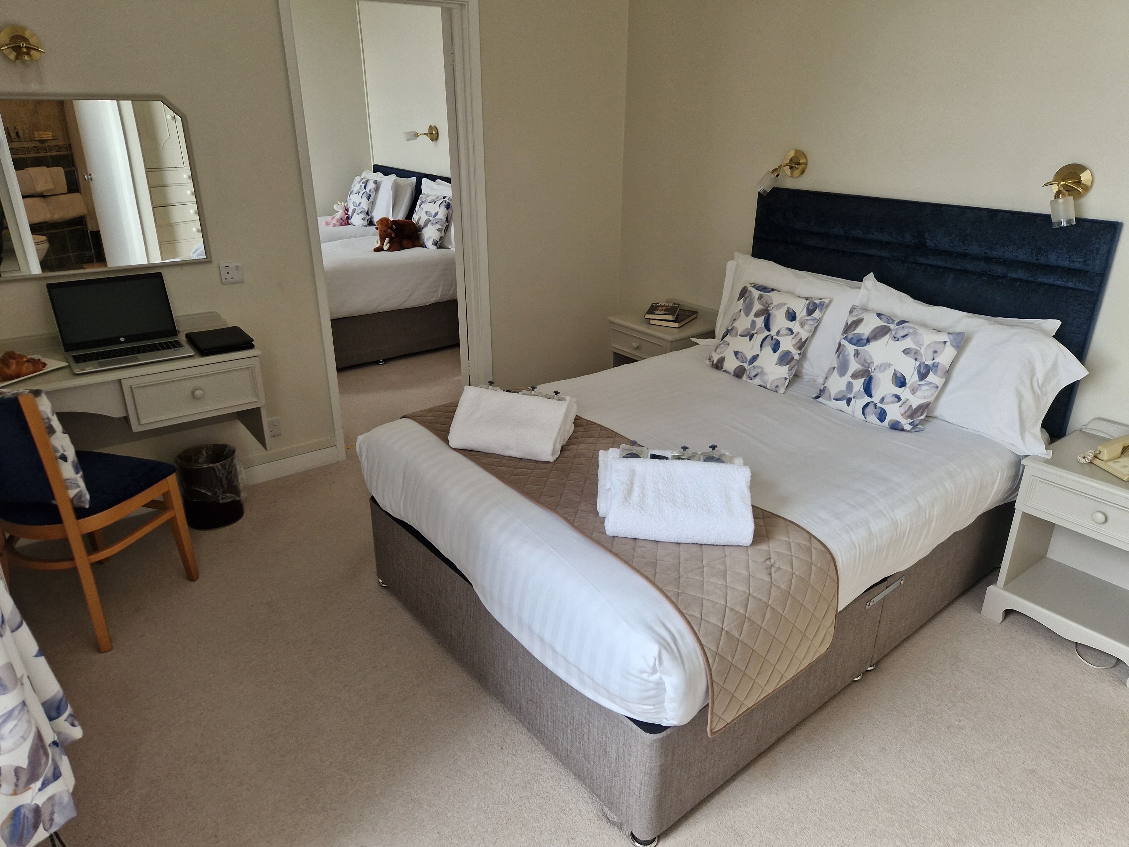 A neatly arranged hotel room with a bed, a desk, a chair, and a mirror.