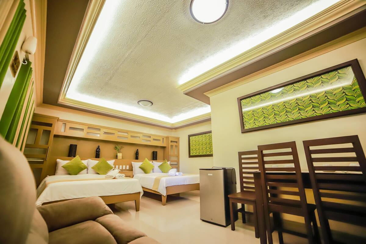A hotel room with two beds, a refrigerator, and a seating area with chairs.