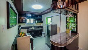 A modern kitchen with dark cabinets, a stainless steel refrigerator, a marble countertop, and a ceiling light fixture. - Villa Esmeralda Bryan's Resort Hotel and Restaurant (Palayan City)