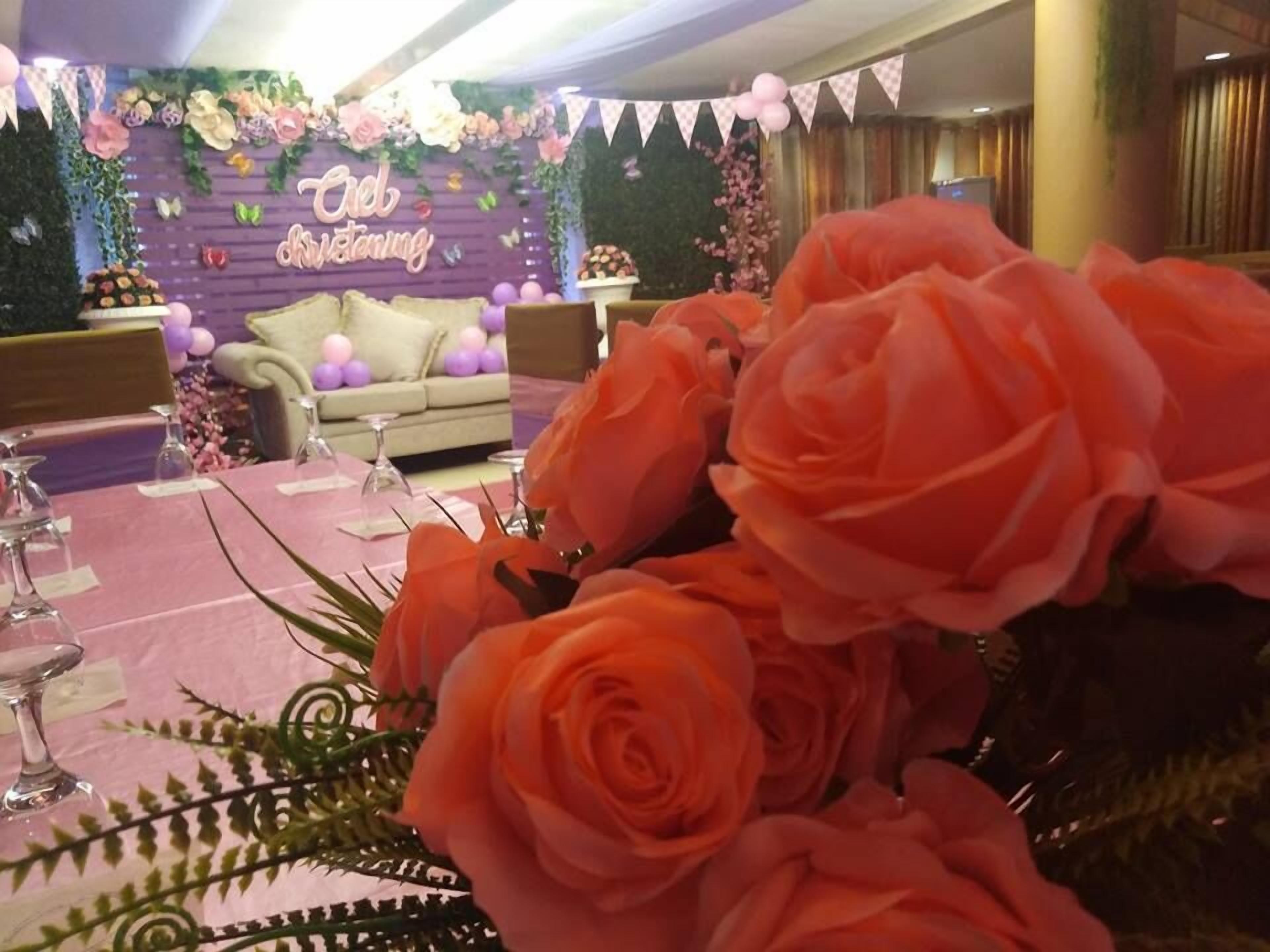 A room with a purple floral backdrop, a sofa, and a table with pink roses.