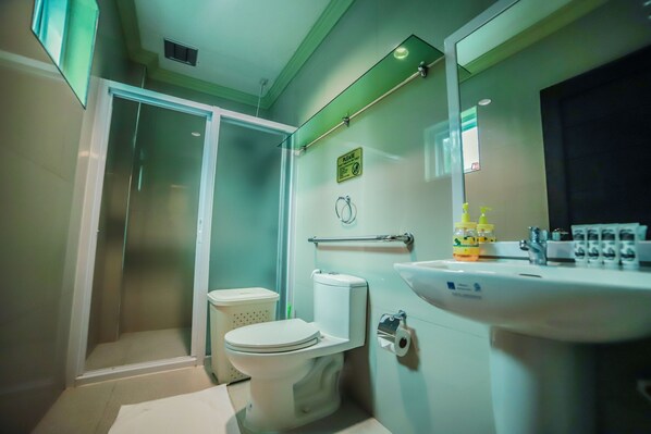 A bathroom with a glass-enclosed shower, a toilet, and a sink with toiletries.