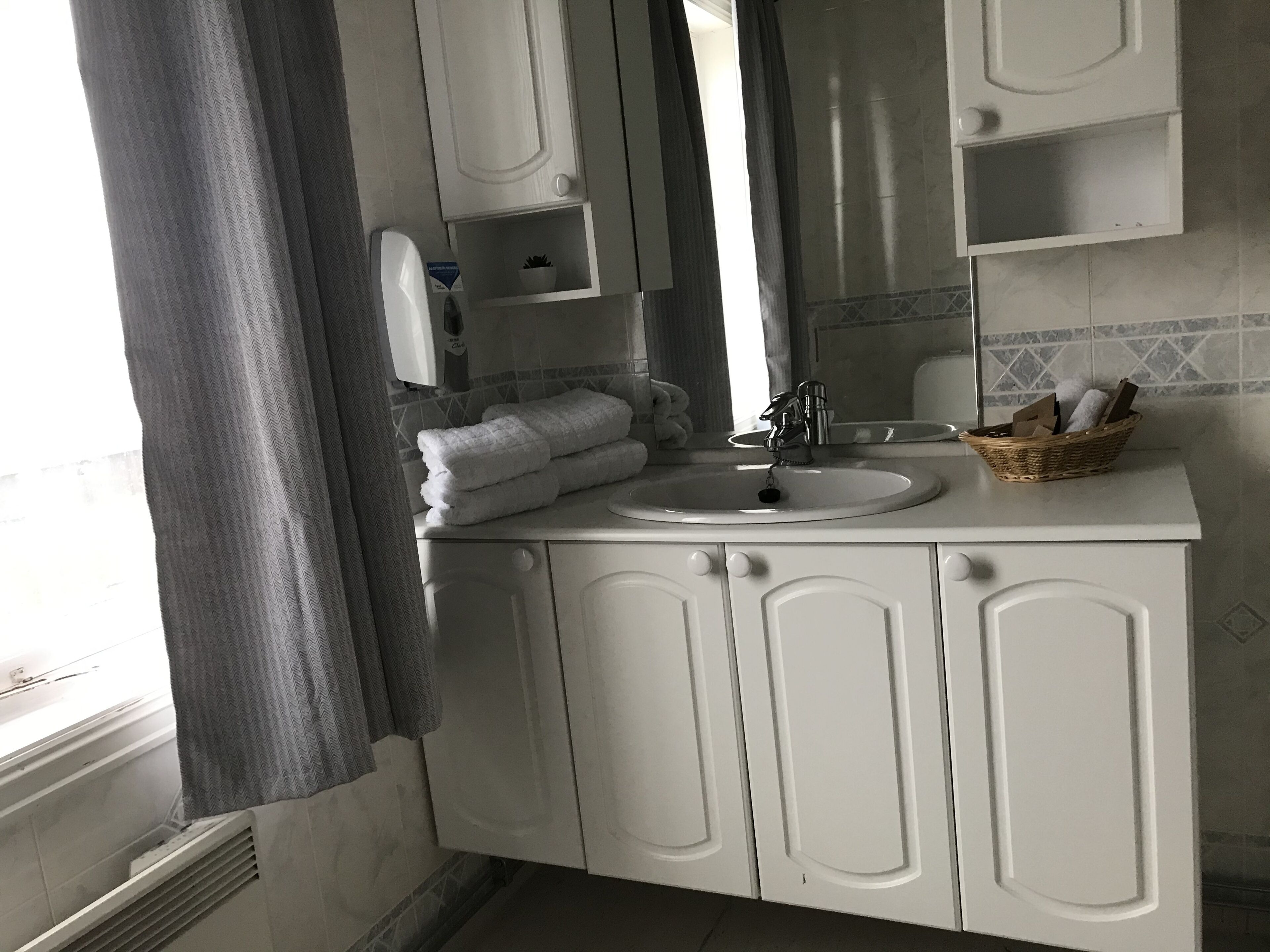 A bathroom with a white sink, a mirror, and a towel rack.