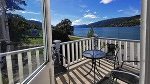 A balcony with a view of a lake and mountains, featuring a table and chairs. - Eidsvåg Fjordhotell (Molde)