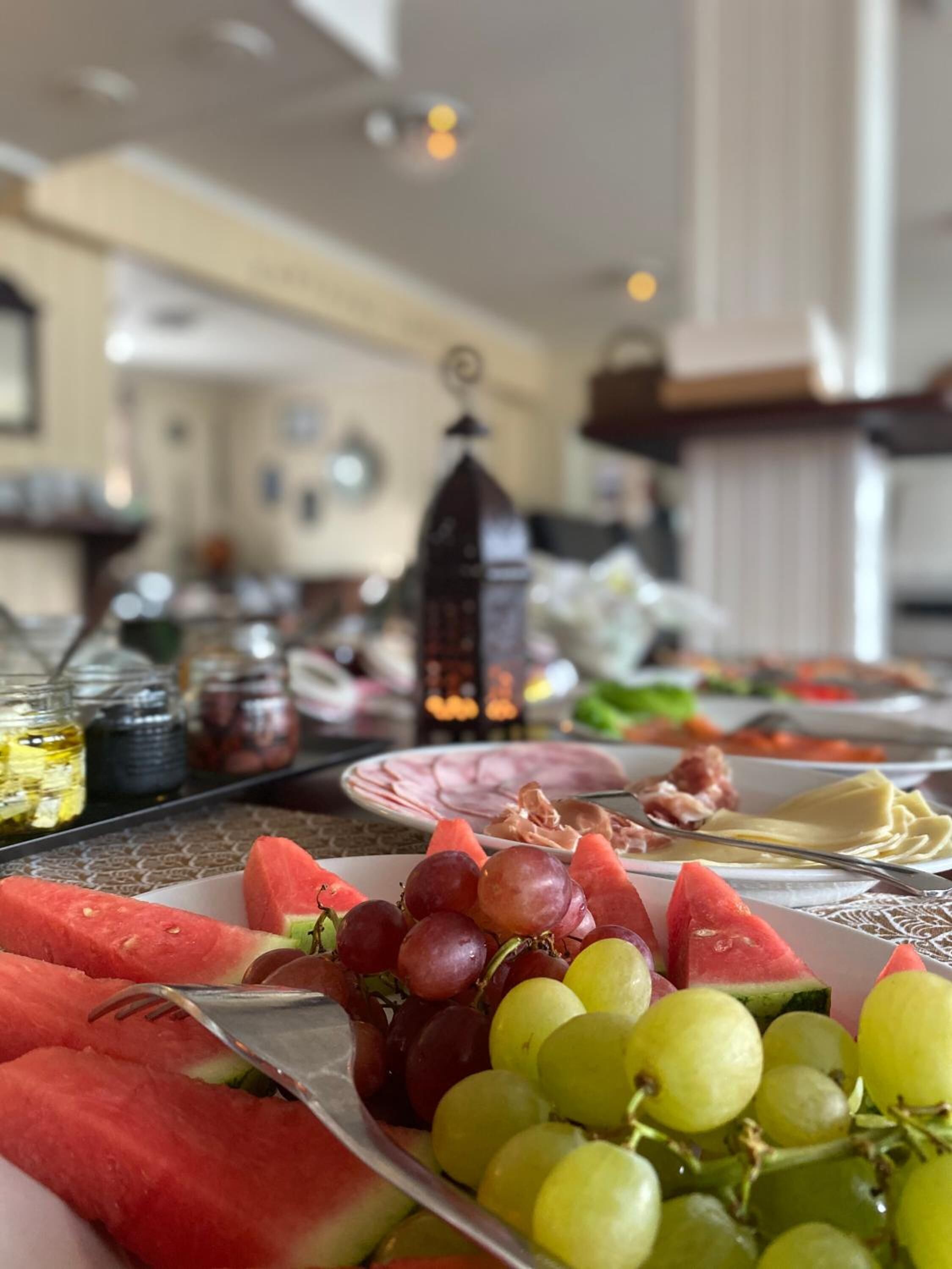 A table with various food items including watermelon, grapes, and ham.