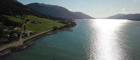 Un lago con un muelle, rodeado de colinas y montañas verdes.