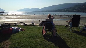 A beach scene with a wheelchair, picnic tables, and people enjoying the view. - Eidsvåg Fjordhotell (Molde)