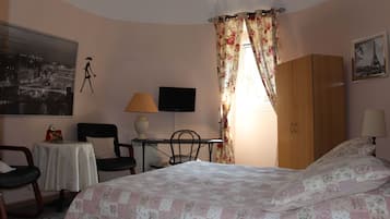 A bedroom with a bed, a desk, a chair, a television, and a wardrobe.