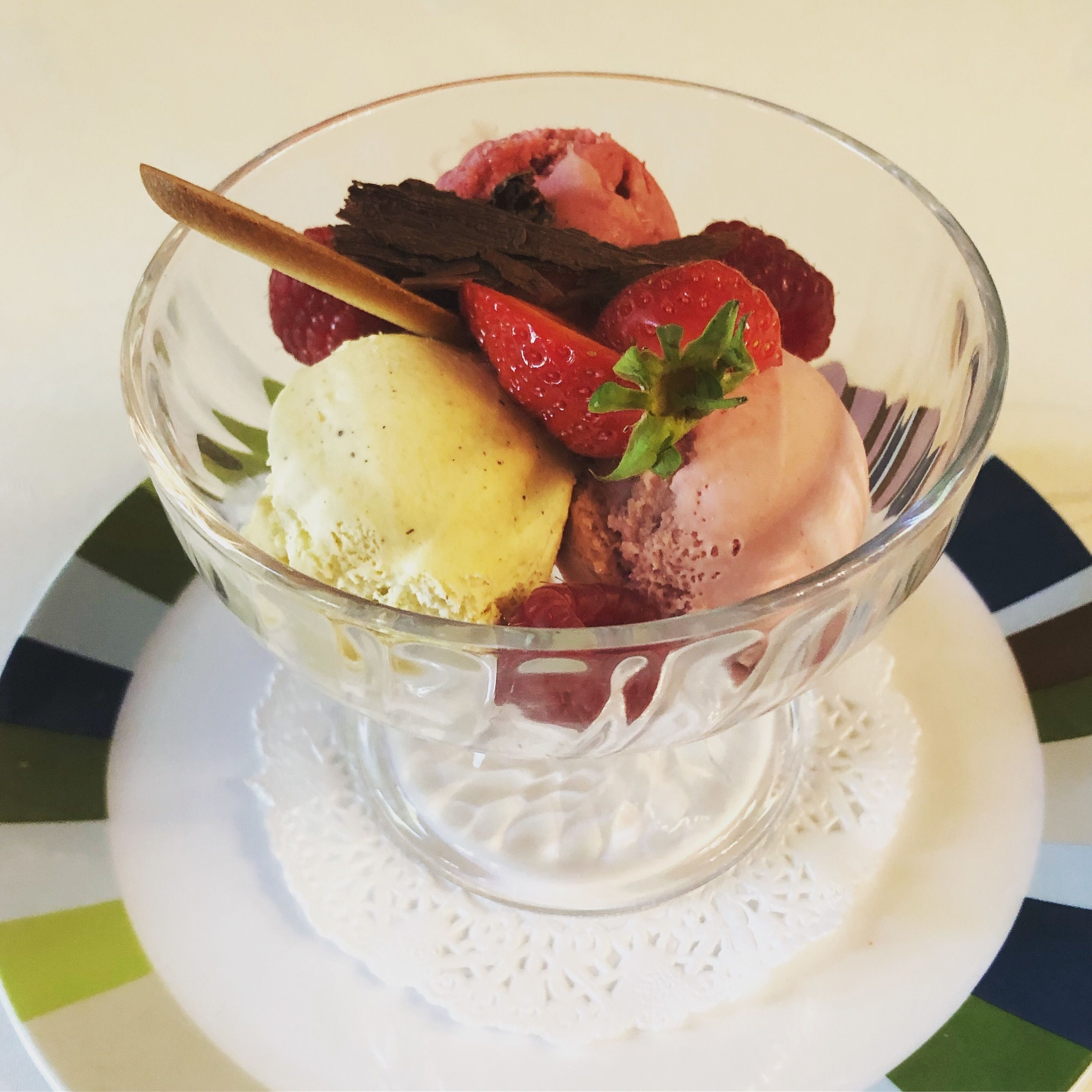 En dessertskål med glass och jordgubbar på en tallrik.