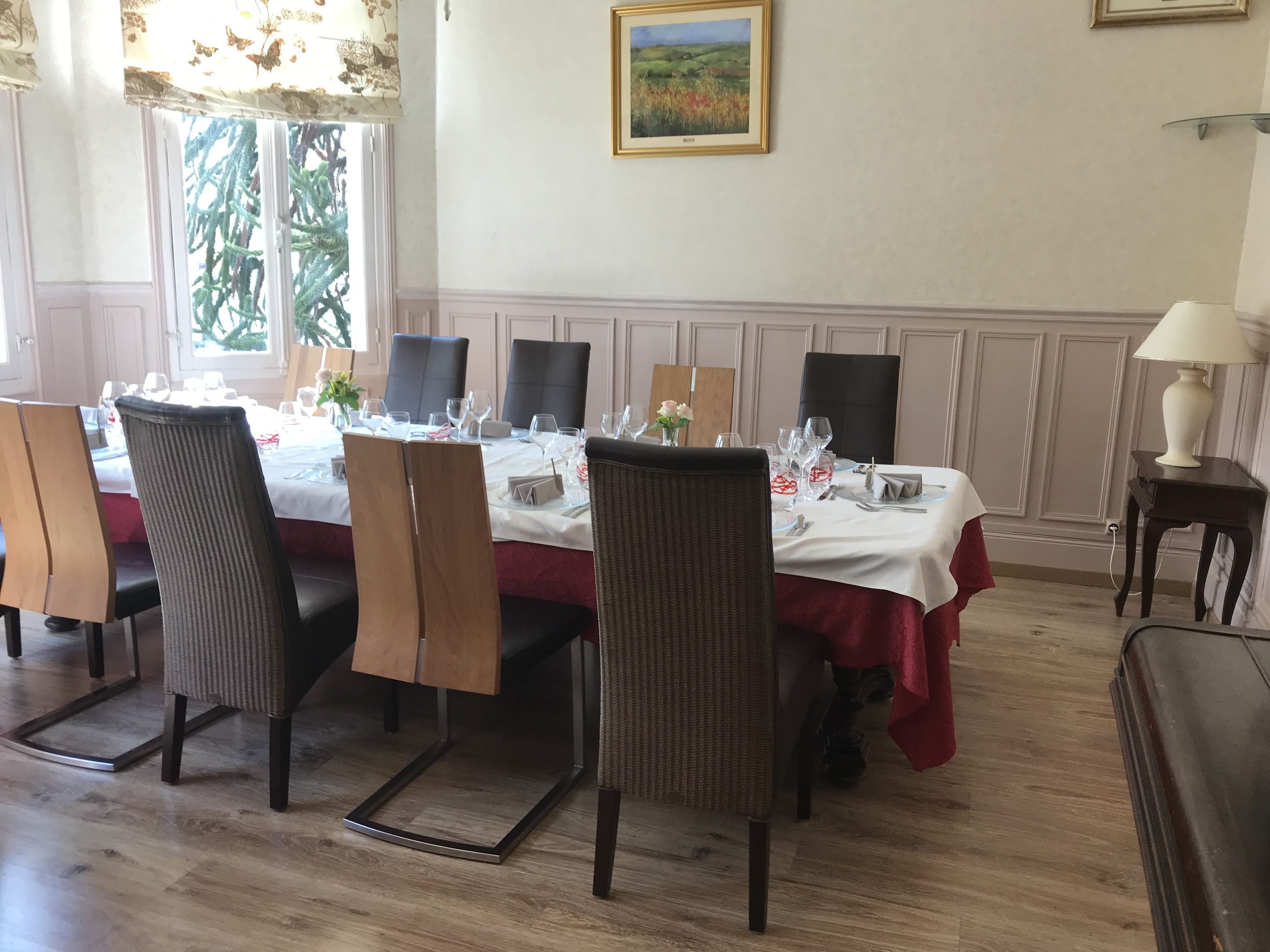 A dining room with a long table set for a meal, surrounded by chairs.