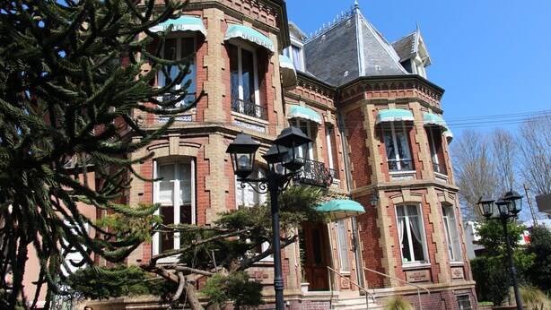 Un edificio de estilo victoriano con fachada de ladrillo, ventanas grandes y una torre.