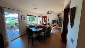 A spacious living area with a dining table, chairs, a TV, and a ceiling fan.