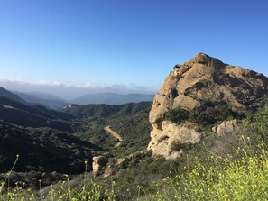 Un paisaje montañoso con una formación rocosa destacada y un sendero de tierra.