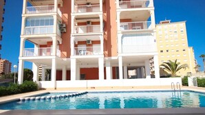 Un hôtel à plusieurs étages doté de balcons, d’une piscine et surplombant un ciel d’un bleu limpide.