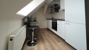 Eine kompakte Küche mit hohen Decken, einem Oberlicht, einem Barhocker, einer Kaffeemaschine und modernen Geräten.