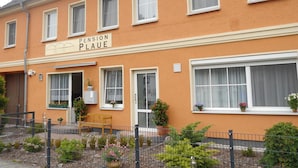 Ein zweistöckiges Gebäude mit einem Schild, auf dem "Pension Plaue" steht.