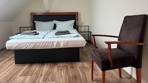 Ein Schlafzimmer mit einem Bett, einem Sessel und einem Nachttisch.