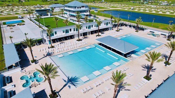 A resort with multiple swimming pools, a tennis court, and a large building with a blue roof. - Shark Shack ~ 3rd Row Home ~ Holiday Addition ~ Ocean View ~ Basketball Goal (Bolivar Peninsula)