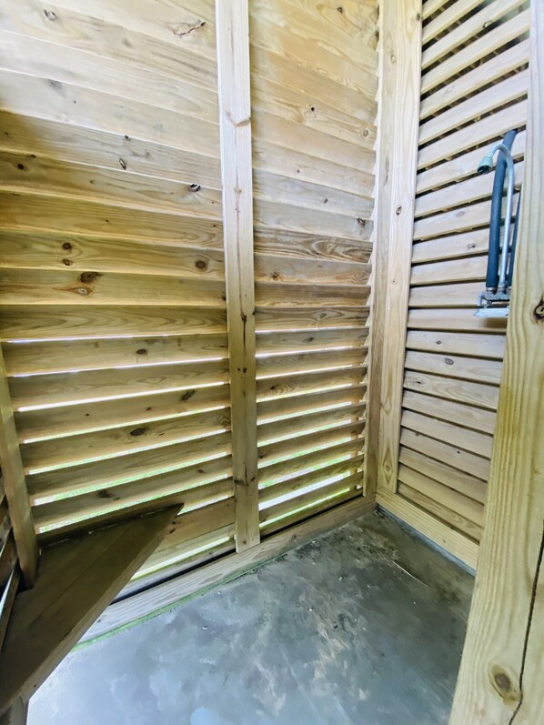 A wooden room with slatted walls, a metal pipe, and a concrete floor. - Shark Shack ~ 3rd Row Home ~ Holiday Addition ~ Ocean View ~ Basketball Goal (Bolivar Peninsula)