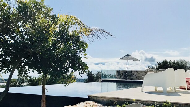 A pool area with a table and chairs, surrounded by rocks and cacti.