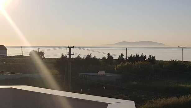 Un balcón con vistas al mar y montañas a lo lejos.