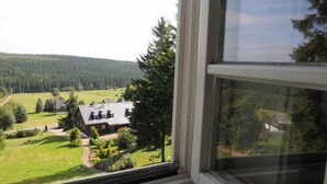 Blick aus einem Fenster auf eine ländliche Landschaft mit einem Haus und einem Wald.