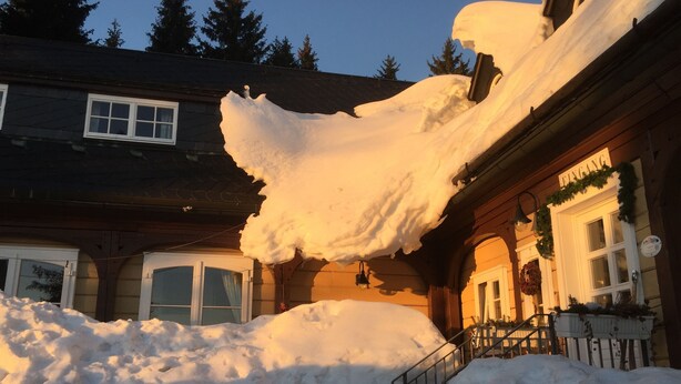 Ein Gebäude mit einer dicken Schneedecke auf dem Dach und um den Eingang.