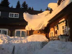 A building with a large snow accumulation on the roof and around the entrance.