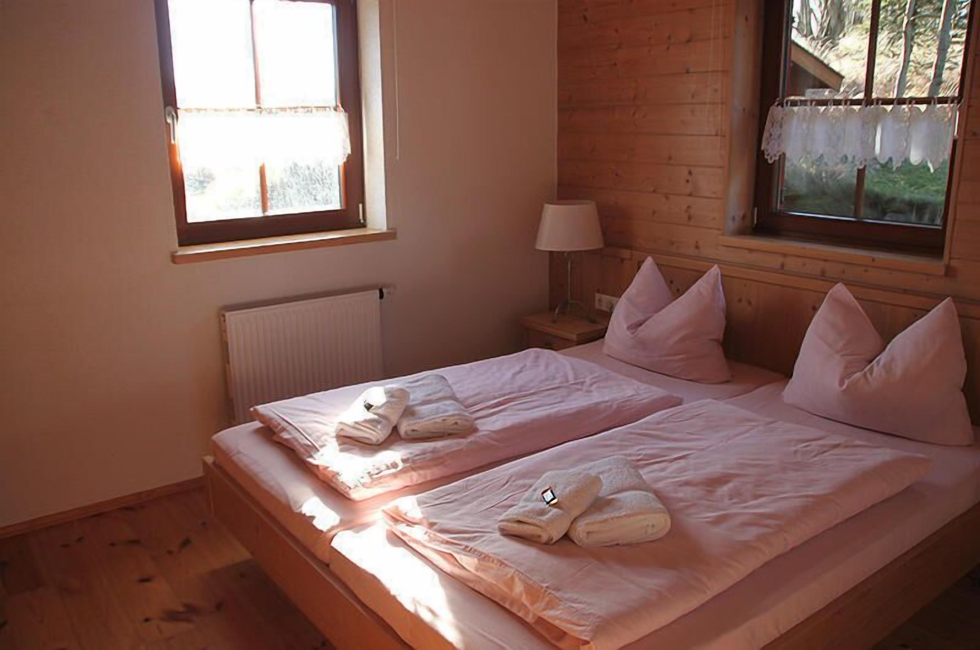 Una habitación con dos camas, una ventana, un radiador y una lámpara.