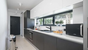 A modern kitchen with dark cabinets, a stainless steel refrigerator, and a window providing natural light.