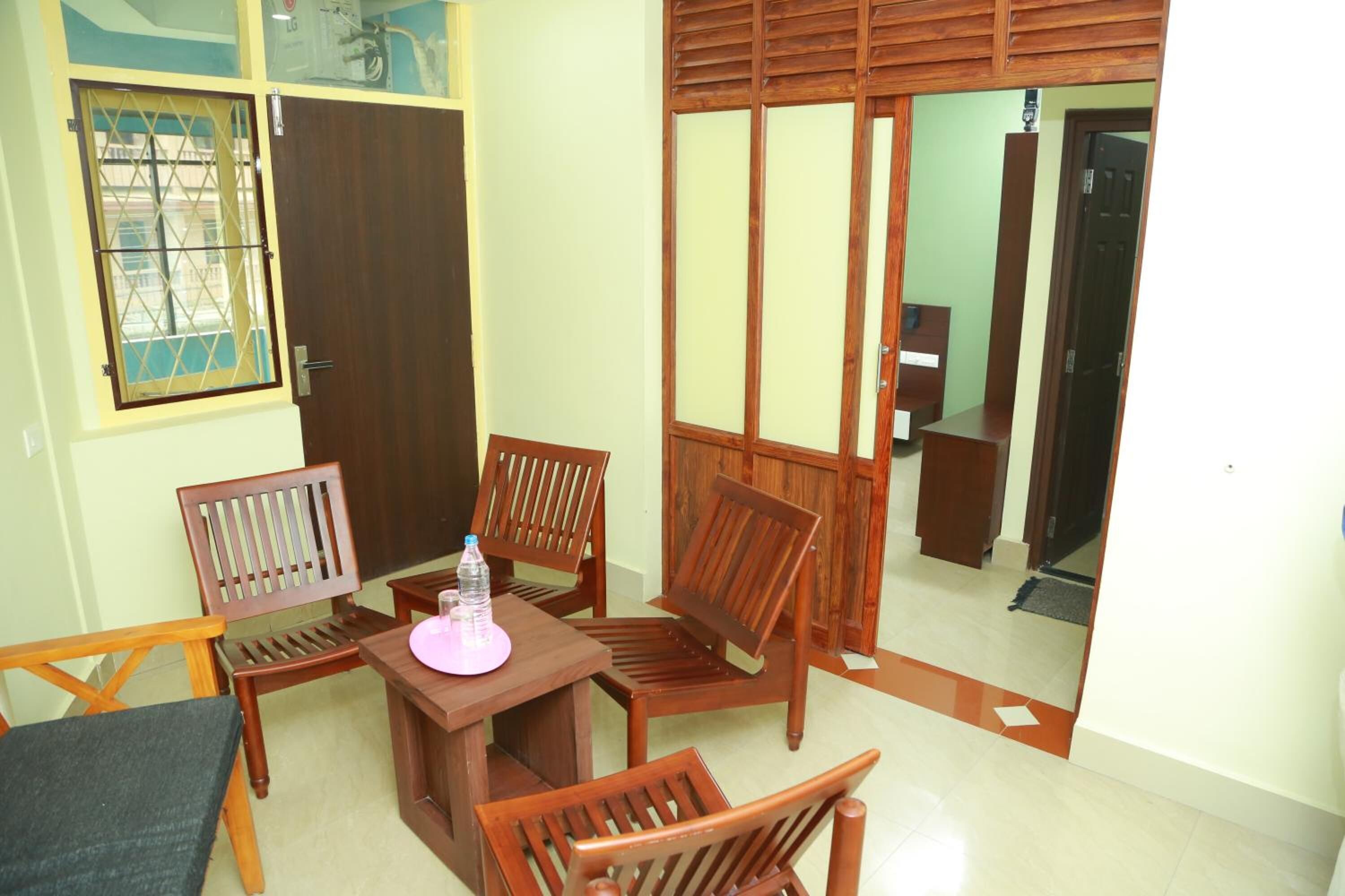 A room with a wooden table and chairs, a small table with a pink object, and a sliding door.