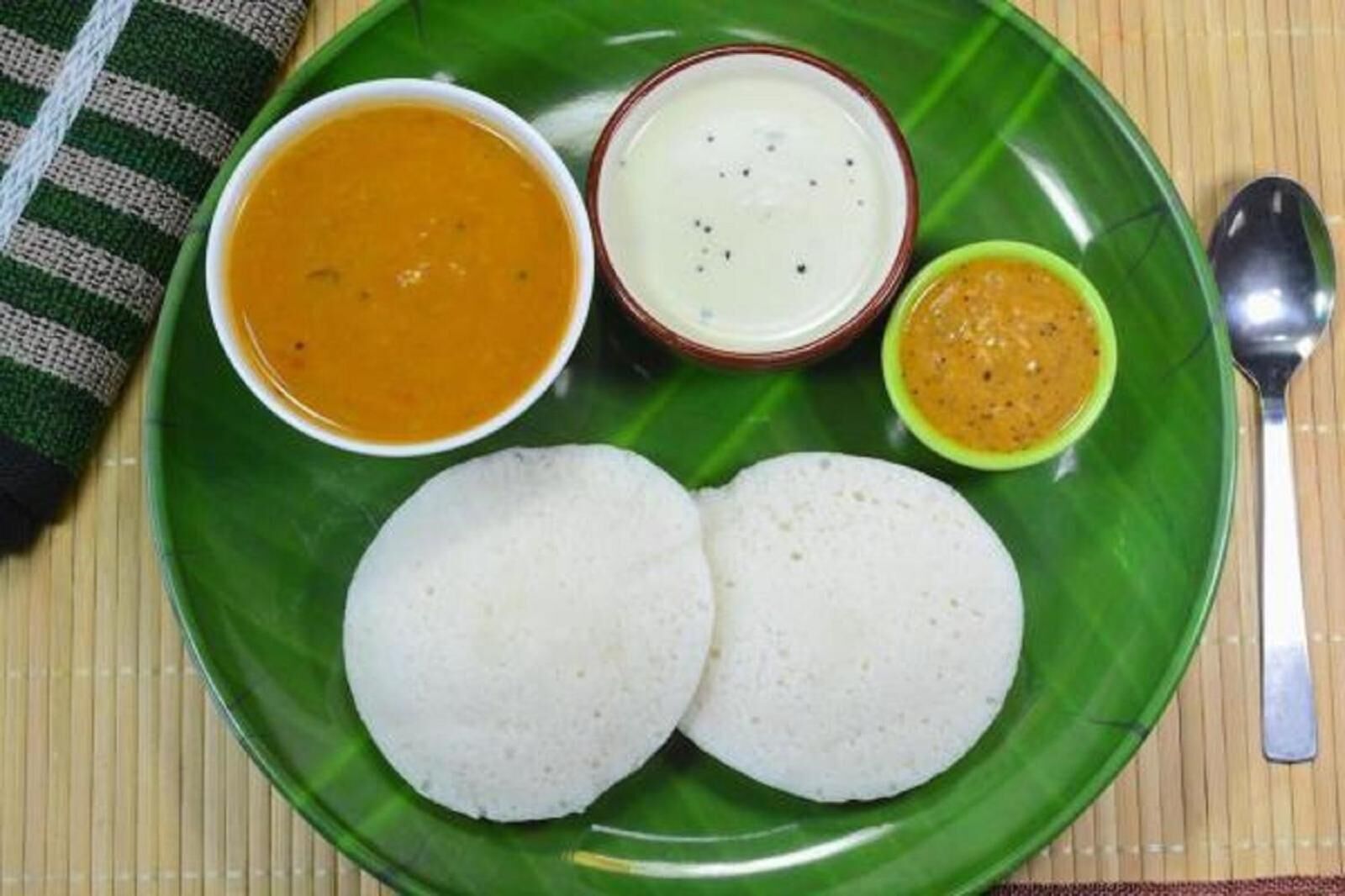 En tallerken med to hvide risboller, en skål orange karry, en skål hvid suppe og en lille skål gul karry.