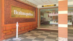 A reception area with a 'Brahmaputra' sign, a 'WELCOME' sign, and a checkered floor. - Hotel Brahmaputhra (Chavakkad)