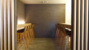 A conference room with a long table and chairs, a neutral-colored wall, and a ceiling light.