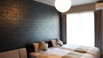 Habitació d'hotel amb un llit gran, un sofà, una paret amb textura i una finestra amb cortines.