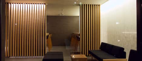 Un área de espera moderna con listones de madera, asientos y una pequeña mesa.