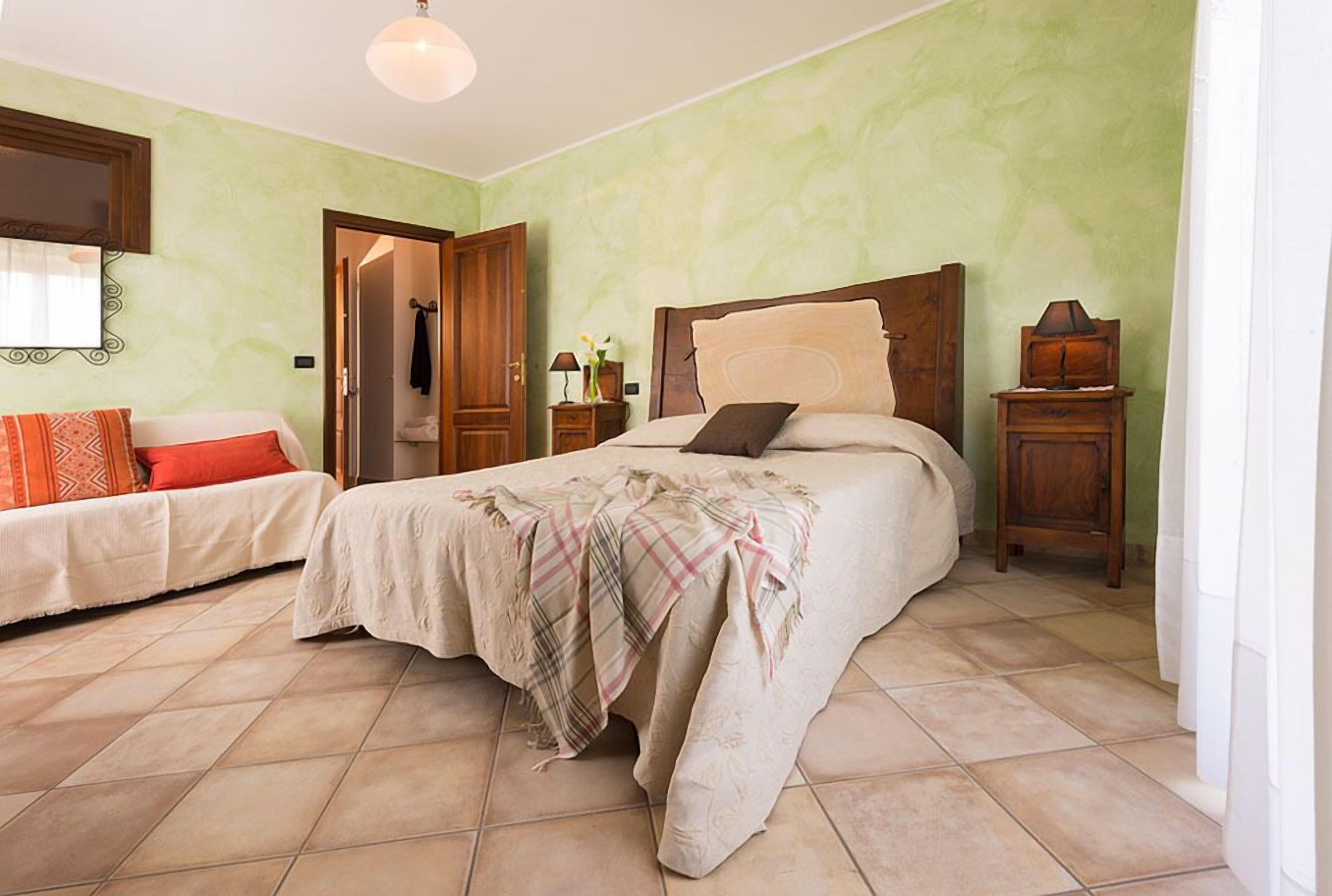 Un dormitorio con cama, mesita de noche y una silla.