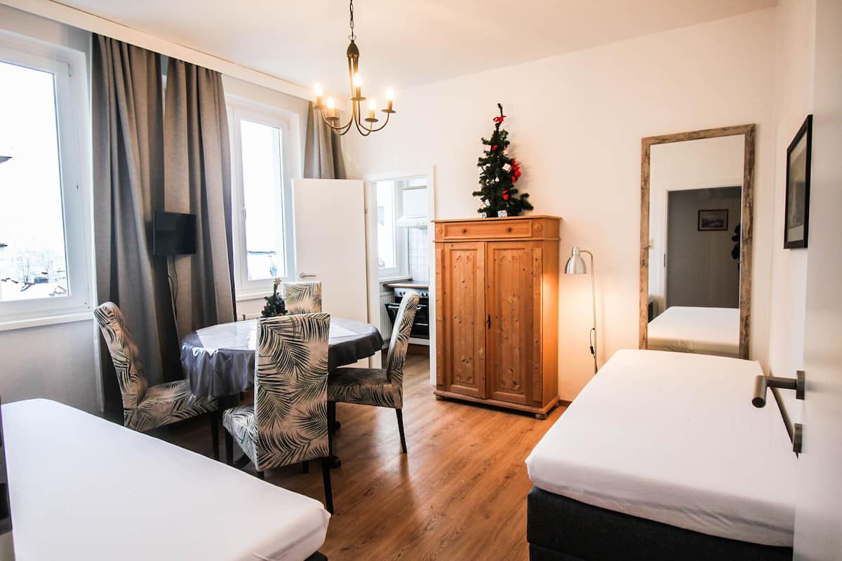 Una habitación de hotel con dos camas, una mesa de comedor con sillas de estampado de cebra, un armario de madera, un pequeño árbol de Navidad y un espejo en la pared.