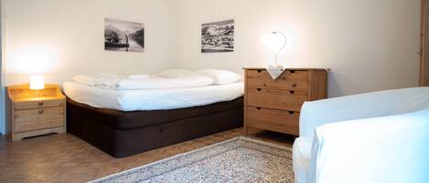 A bedroom with a bed, bedside tables, a lamp, and two wall-mounted pictures.