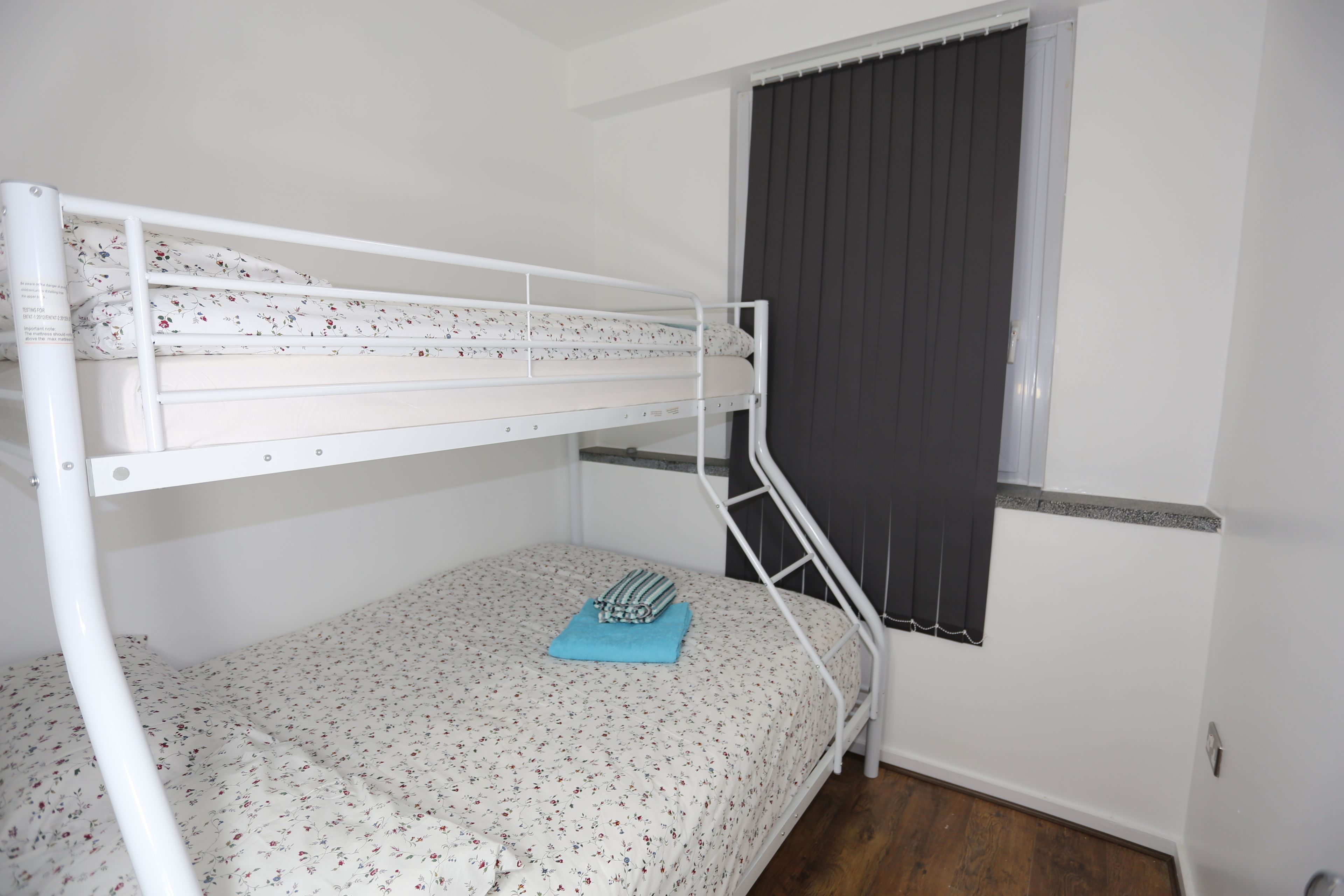 A bunk bed with floral bedding and a blue towel.