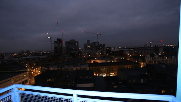 A nighttime cityscape with buildings and construction cranes.