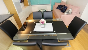 A dining area with a glass table, black chairs, and a vase with flowers.